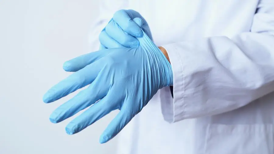 Medical professional donning latex gloves