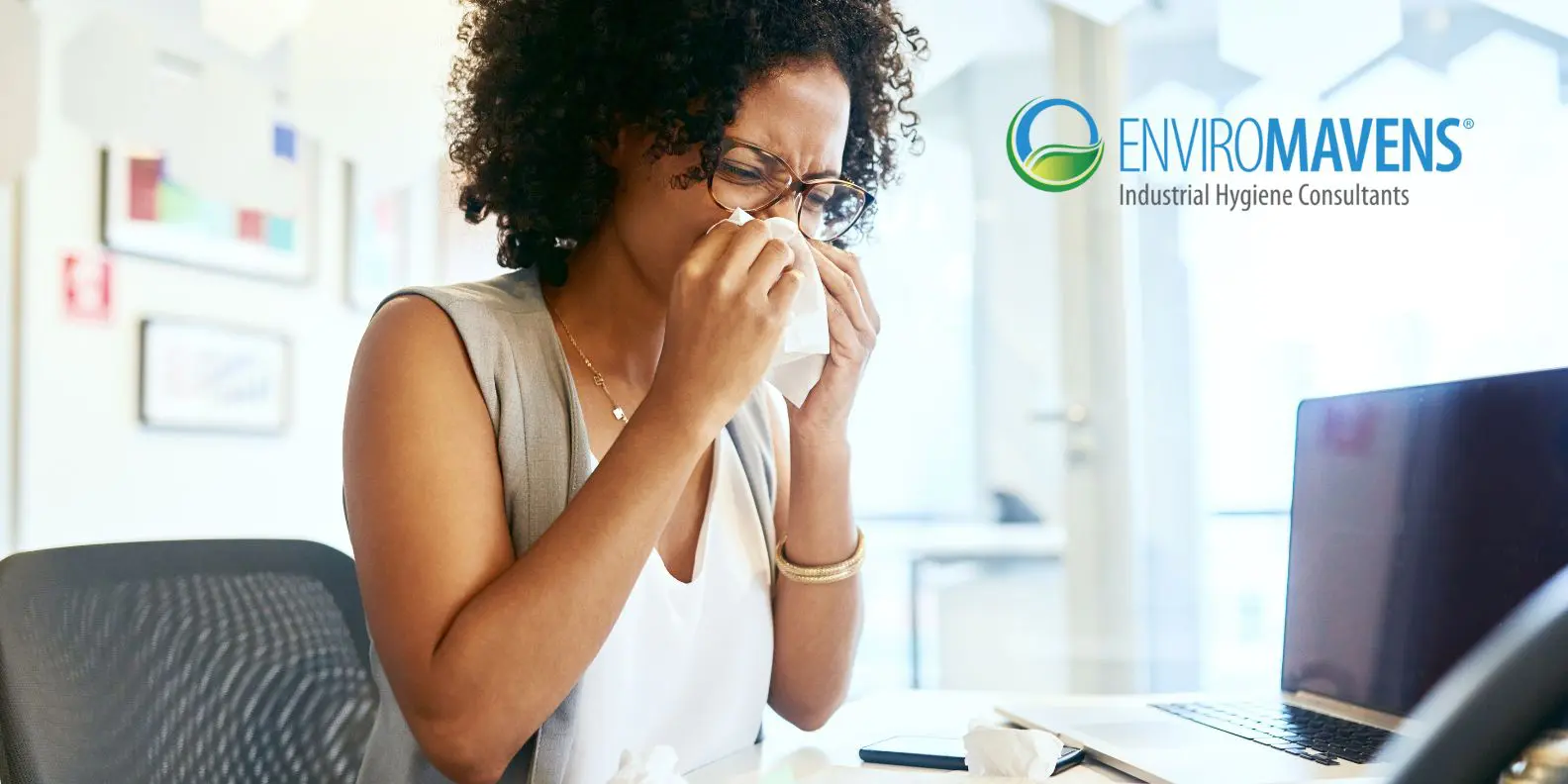 Sneezing at desk with laptop