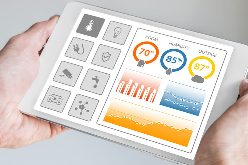 A person holding a tablet displaying the humidity and home temperature