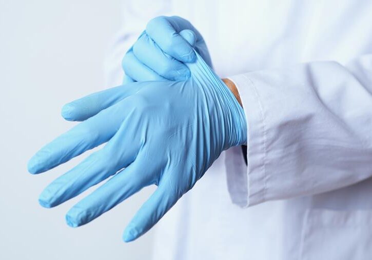Medical professional donning latex gloves