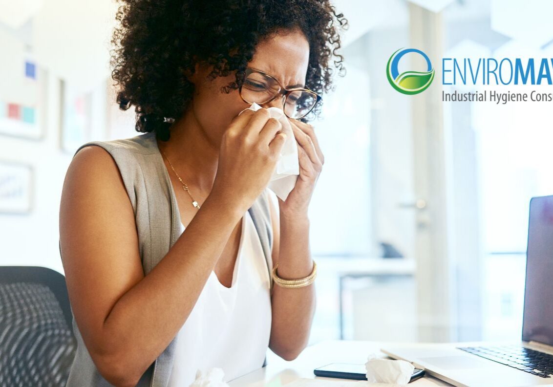 Sneezing at desk with laptop